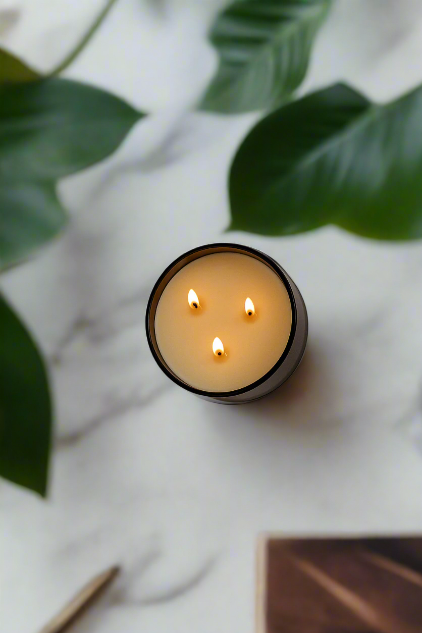 Candle with three flames on a marble surface with green leaves.Transform your space into a serene retreat with our new Signature 3-Wick Candle in Lavender + Cedar—a calming, grounded blend designed to fill larger spaces with soft, natural fragrance and a warm, even glow. Topped with a black metal lid.
Hand-poured in Austin, Texas, this candle is crafted with 100% soy wax and pure essential oils, offering a clean, non-toxic burn you can feel good about.