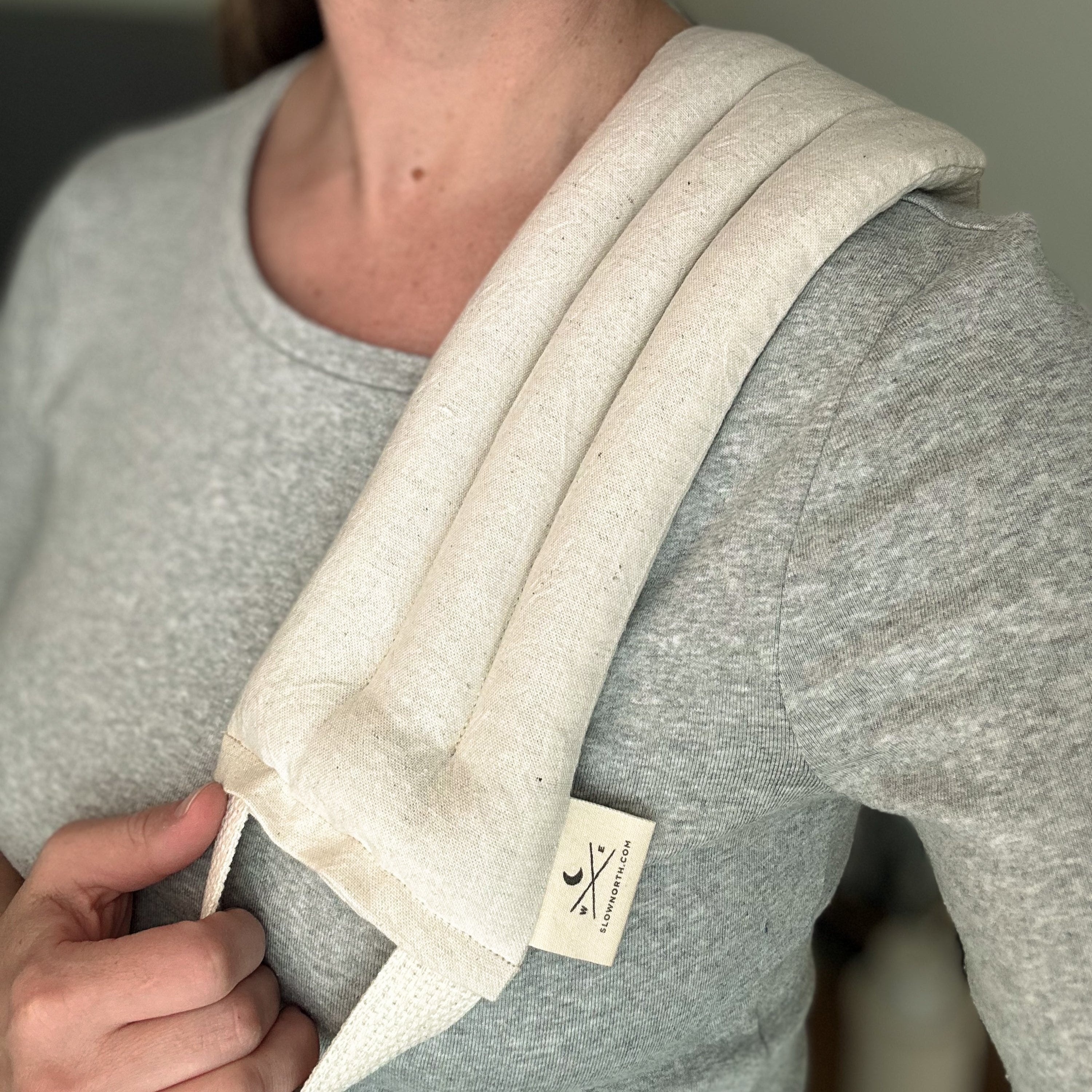 Person wearing a gray sweatshirt with a beige fabric strap over their shoulder, featuring a brand label. A natural linen and cotton weighted neck wrap to ease the stress away.
Melt away the tension: Let this cheerful therapy pack melt away the aches and pains as it drapes around your neck and shoulders.
Relax in your own way: This well-designed therapy pack neck pillow can be applied warm or cold depending on your preference.
Soothe tension & aches: Cold and warm therapy packs can work wonders for pain