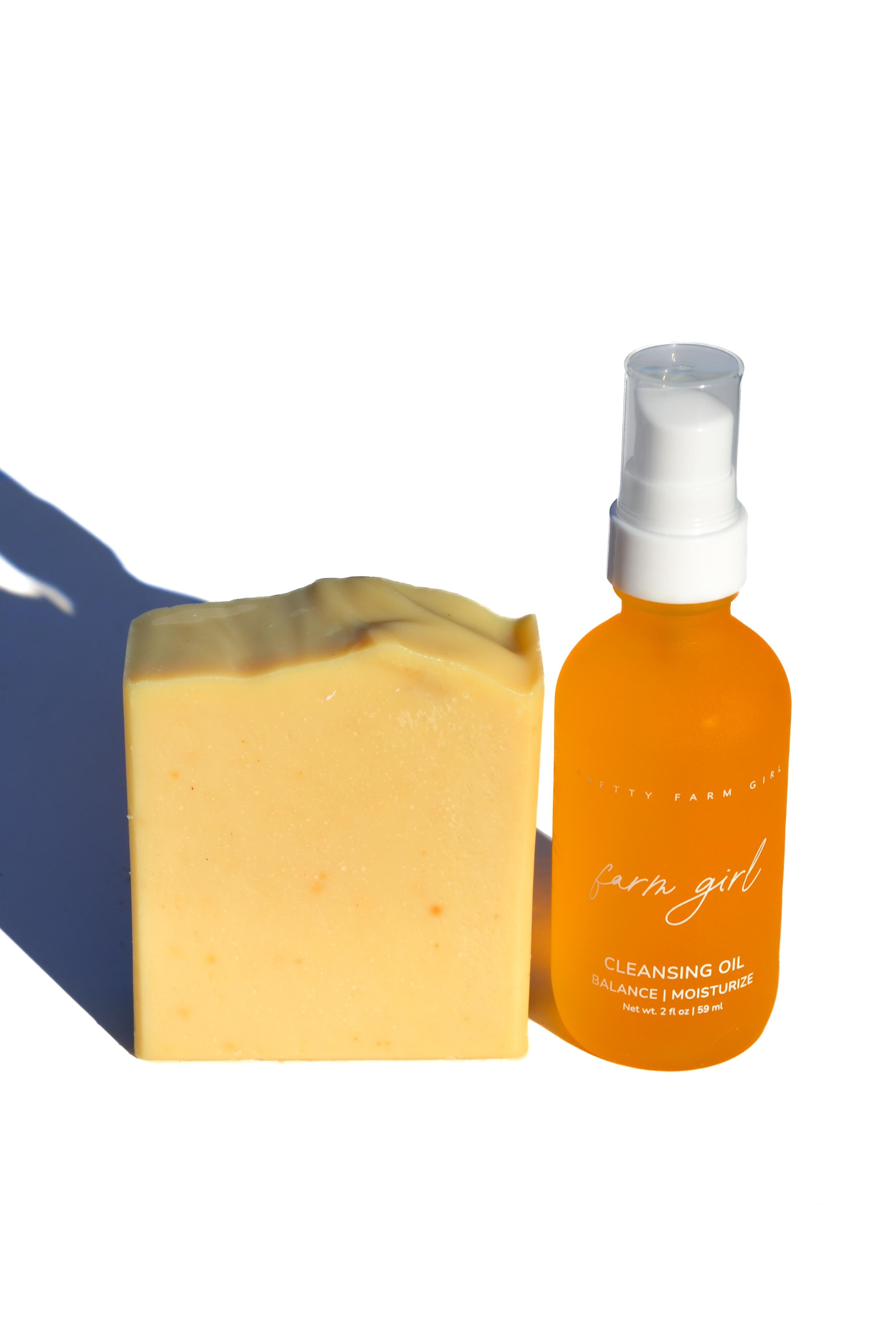 Bar of soap and bottle of cleansing oil on a white background. Orange bottle and jar of facial product on a white background. rosehip and rose essential oils serum and facial cleansing lotion