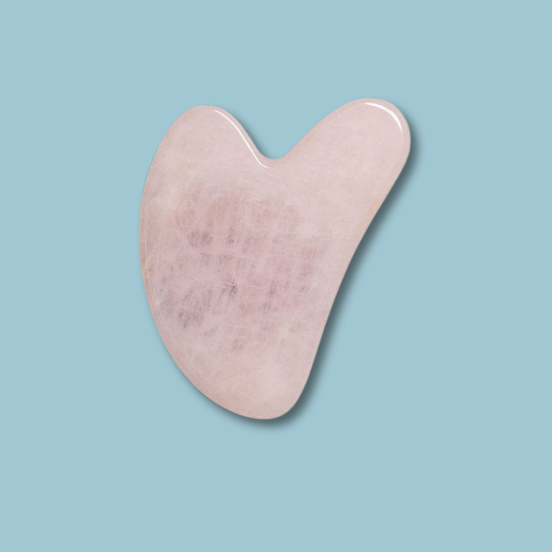 Pink gua sha tool on a light blue background. natural face lift for aging and eye puffiness