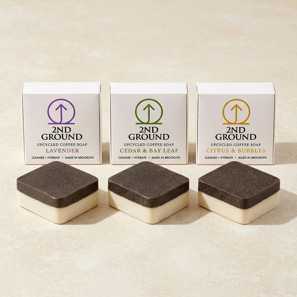 Three boxes of 2nd Ground upcycled coffee soap with corresponding soap bars on a beige background. Collection of 2nd Ground upcycled coffee soap bars on a stone surface with branded boxes. comfrey salve for healing arthritis workout recovery drawing salve