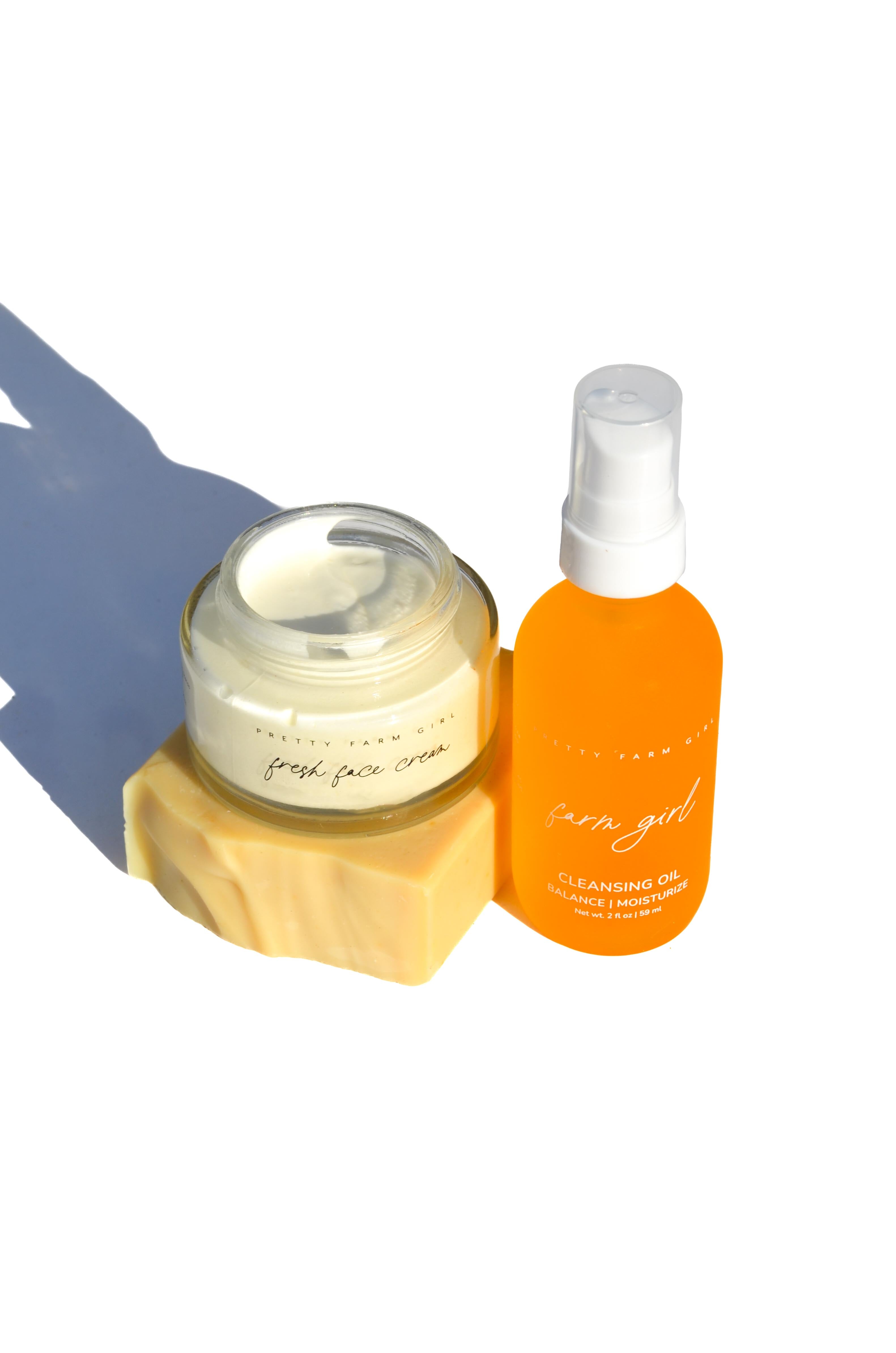 Orange bottle and jar of facial product on a white background. rosehip and rose essential oils serum and facial cleansing lotion