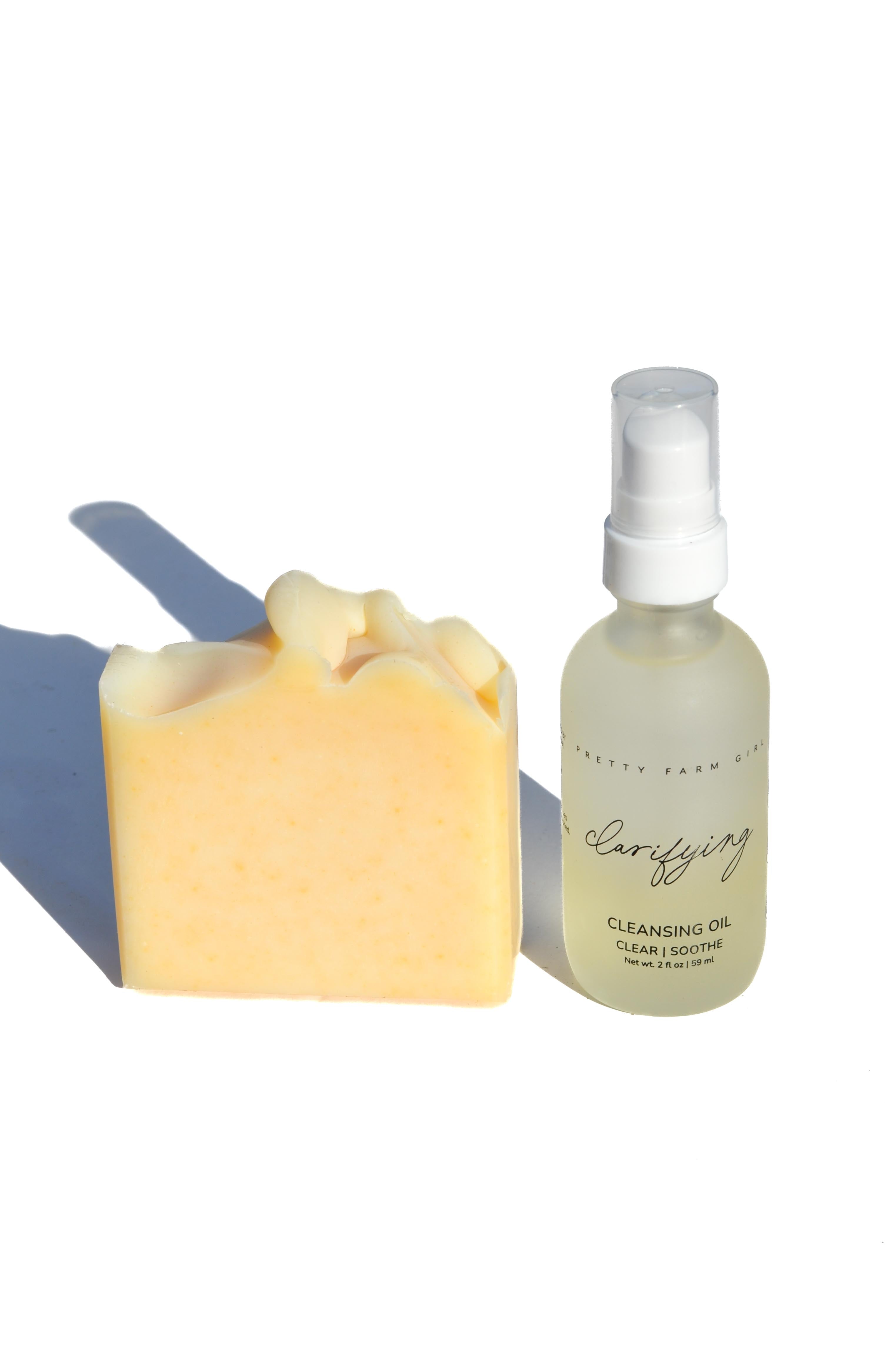 Bar of soap and bottle of cleansing oil on a white background. Two skincare products, a jar and a bottle, on a white background with a soft shadow. tallow arnica calendula tea tree pretty farm girl facial care organic soap serum and lotion 