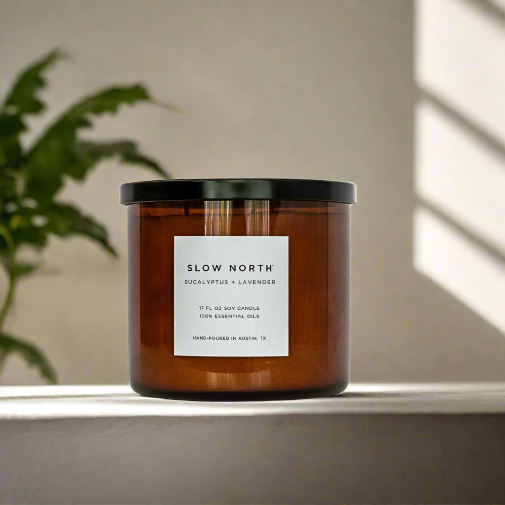Candle with 'Slow North' label on a surface with a plant and light in the background. Transform your space into a serene retreat with our new&nbsp;Signature 3-Wick Candle in&nbsp;Eucalyptus + Lavender&nbsp;— a sweet, calming blend designed to fill larger spaces with soft, natural fragrance and a warm, even glow. Topped with a black metal lid.

Hand-poured in Austin, Texas, this candle is crafted with 100% soy wax and pure essential oils, offering a clean, non-toxic burn you can feel good about.