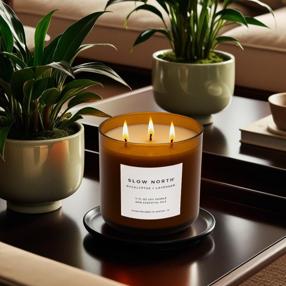 Candle with 'Slow North' label on a table with plants and books in the background. Transform your space into a serene retreat with our new&nbsp;Signature 3-Wick Candle in&nbsp;Eucalyptus + Lavender&nbsp;— a sweet, calming blend designed to fill larger spaces with soft, natural fragrance and a warm, even glow. Topped with a black metal lid.

Hand-poured in Austin, Texas, this candle is crafted with 100% soy wax and pure essential oils, offering a clean, non-toxic burn you can feel good about.