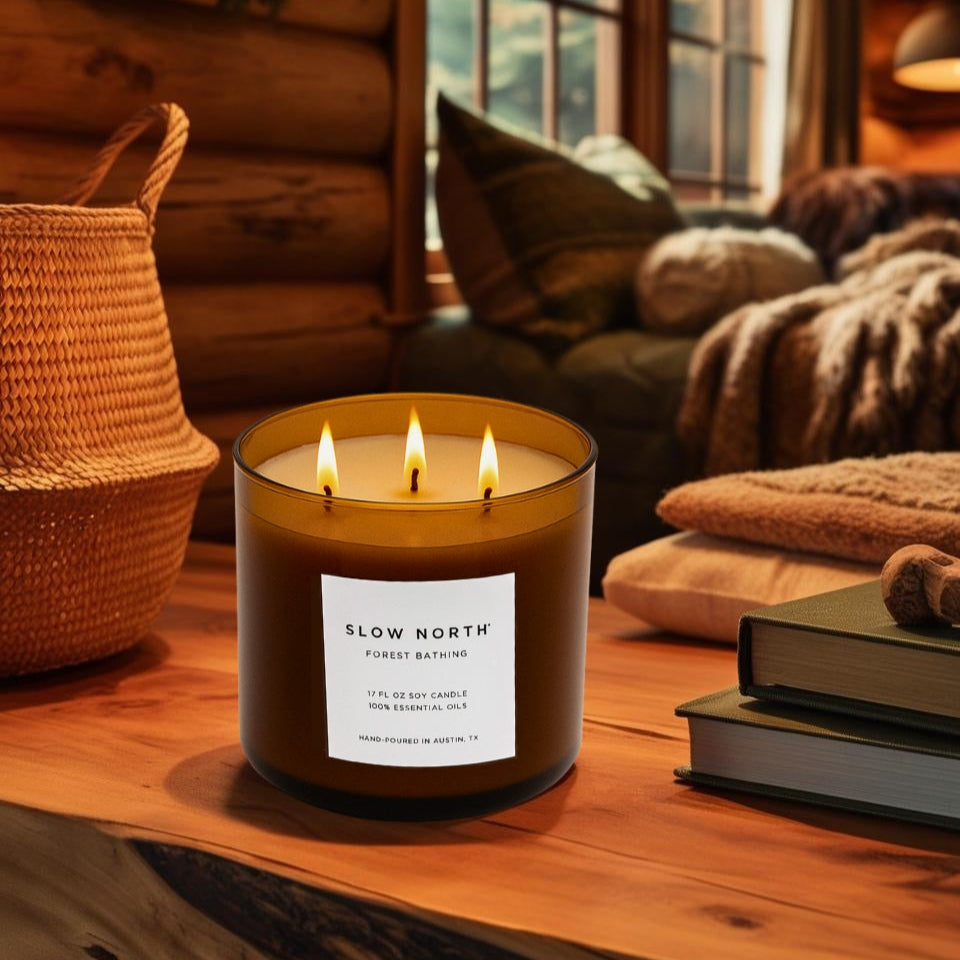 Candle labeled 'Slow North' on a wooden surface with a cozy indoor setting.Step into the stillness of the woods with our&nbsp;Forest Bathing Signature 3-Wick Candle—a grounding, nature-inspired blend designed to fill larger spaces with soft, earthy fragrance and a warm, radiant glow. Topped with a sleek black metal lid for a clean, modern finish.

Hand-poured in Austin, Texas, this candle is made with 100% soy wax and pure essential oils