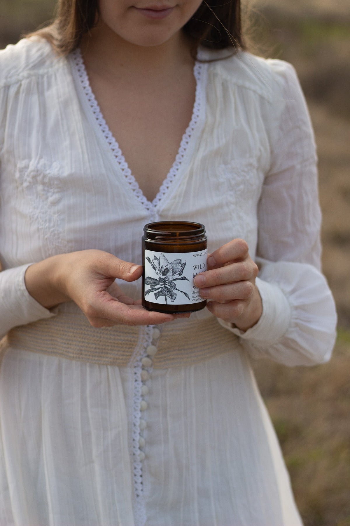 Two unlit amber jar candles on an open book, with Mysterious Fig in the foreground.