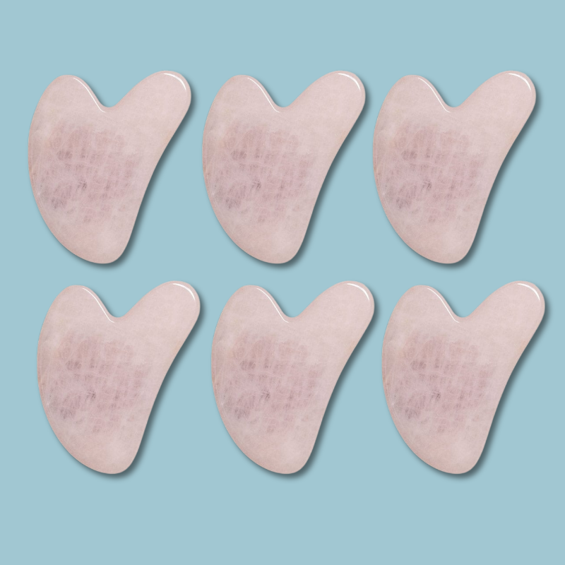 Set of six pink gua sha tools on a light blue background. light therapy for eyes and skin firmness