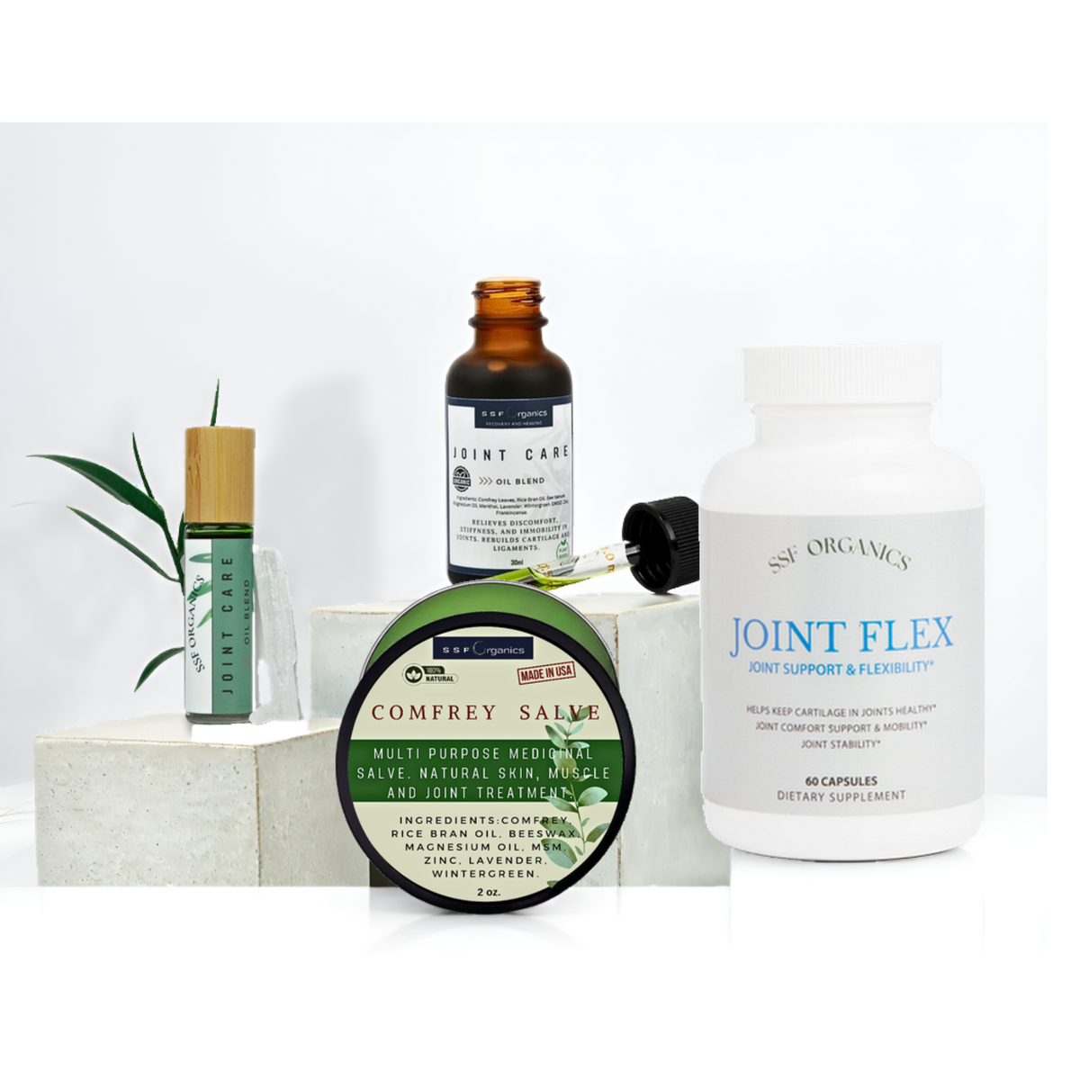 A wellness product bundle on a white background featuring a white bottle of Joint Flex by Nutri Organics, a green and white tin of Comfrey Salve, an amber glass bottle of Joint Care, a green roll-on bottle, and a small green plant sprig.