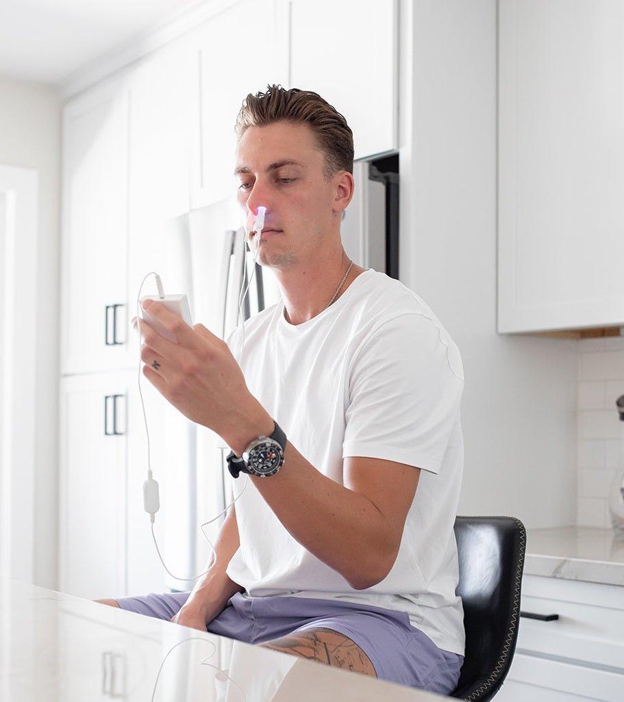 Man sitting in a kitchen holding a glass of water. Mitoredlight apparatus with user manual and cables on a white . background.  blue light at 450 nm for microbial sanitization and red light at 650 nm to boost immunity, reduce inflammation, and improve oxygenation. Portable and lightweight, MitoBOOST™ seamlessly integrates into your daily routine, whether at home or on the go.

By targeting the nasal cavity—a critical site for immune response due to its rich blood capillaries and direct connection to the bra